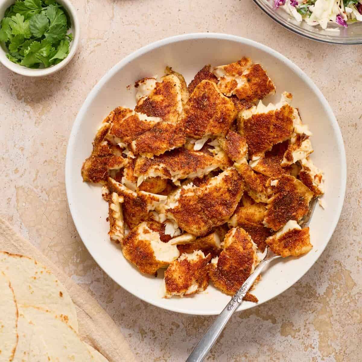 Flaked fish for tacos in bowl.