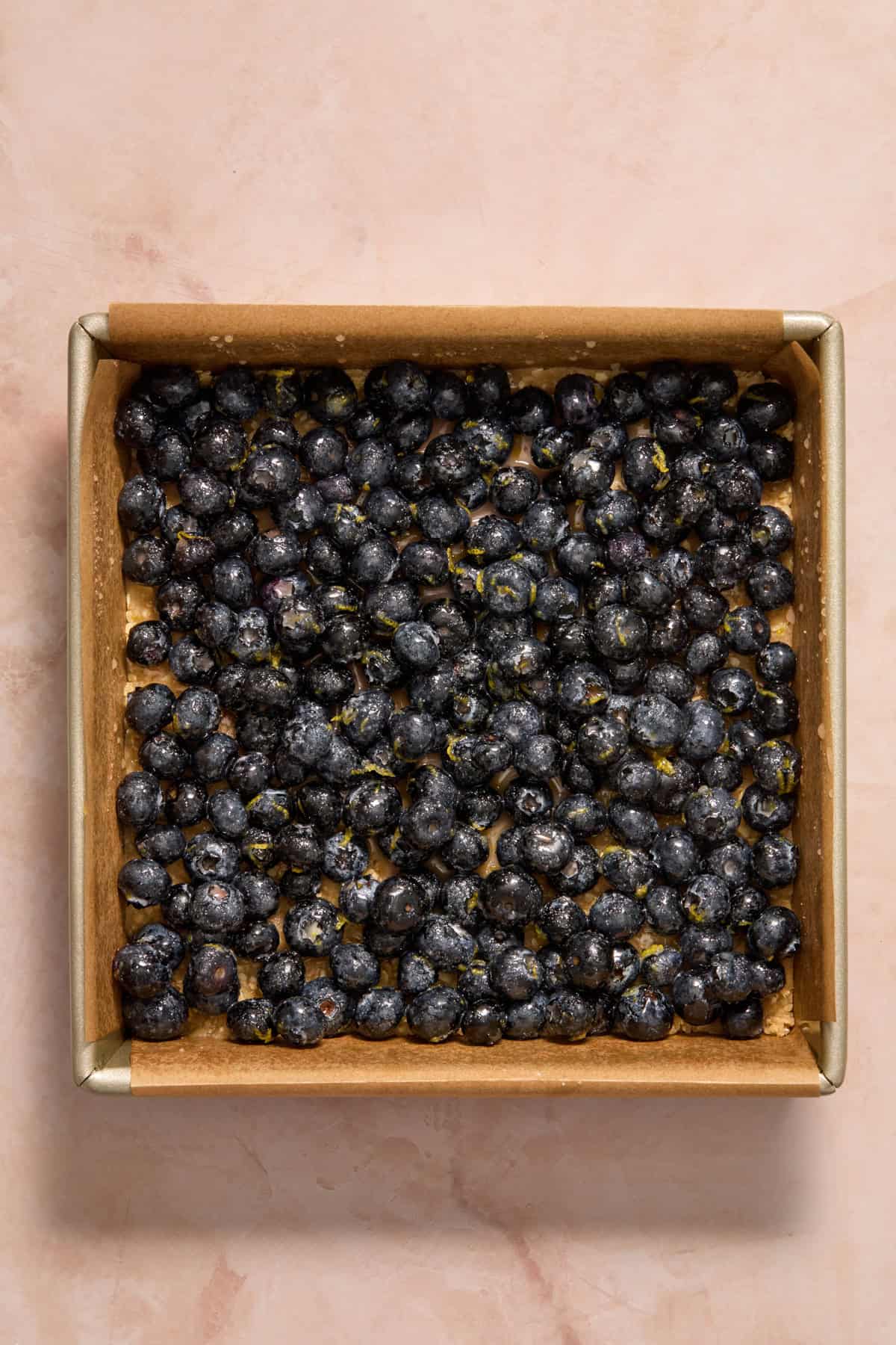 Blueberry lemon mixture added to pan with oat layer.