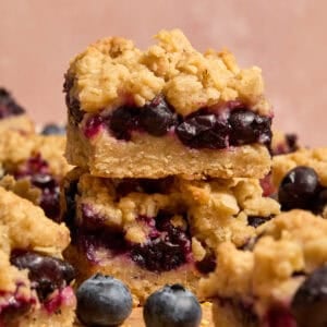 Stacked blueberry lemon bars with blueberries and other bars around it.