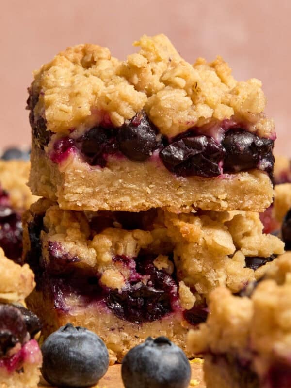 Stacked blueberry lemon bars with blueberries and other bars around it.