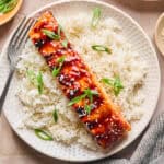 Grilled teriyaki salmon filet over rice with scallions and sesame seeds.