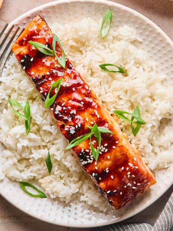Grilled teriyaki salmon filet over rice with scallions and sesame seeds.