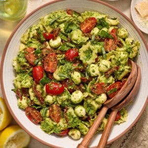 Bowl with prepared pesto tortellini salad topped with fresh chopped basil.