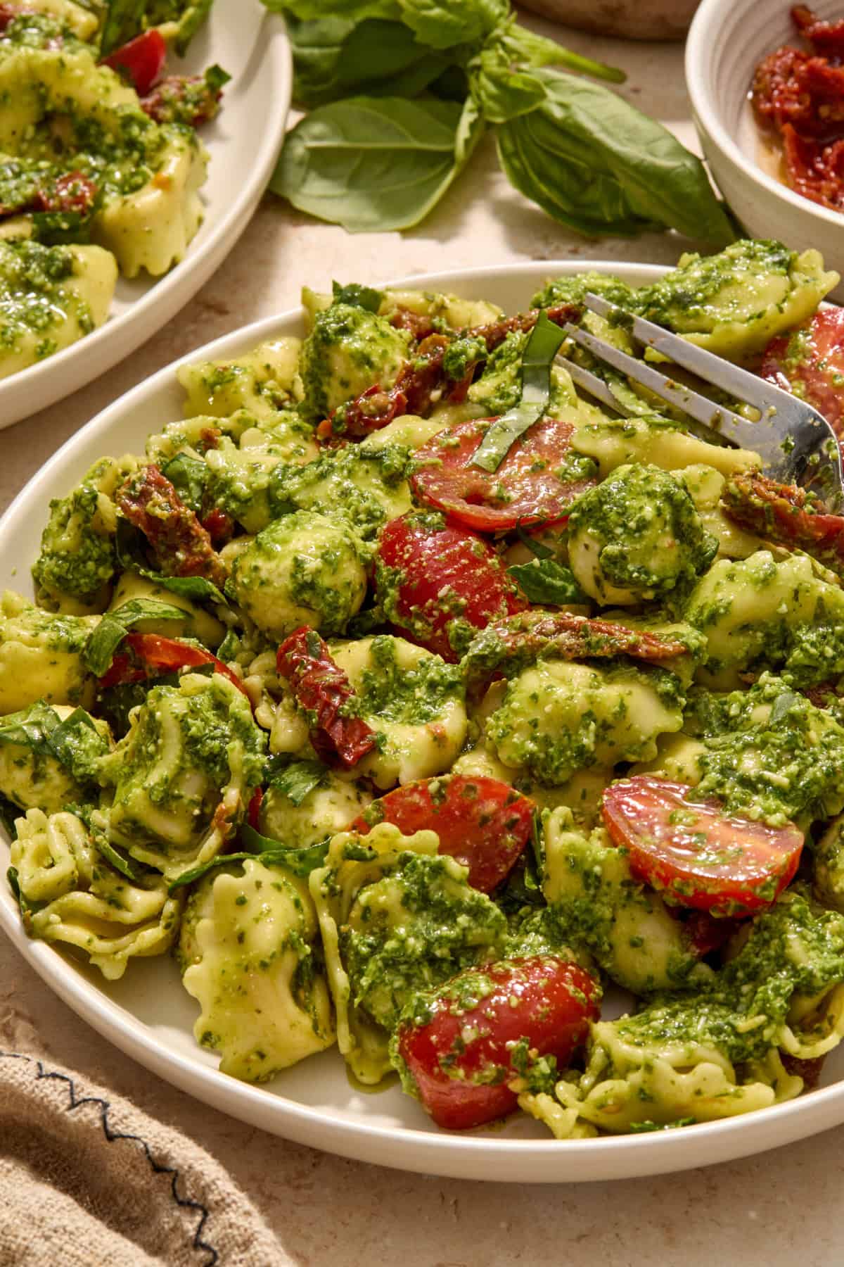 Plate with tortellini pesto salad and fork propped on plate.