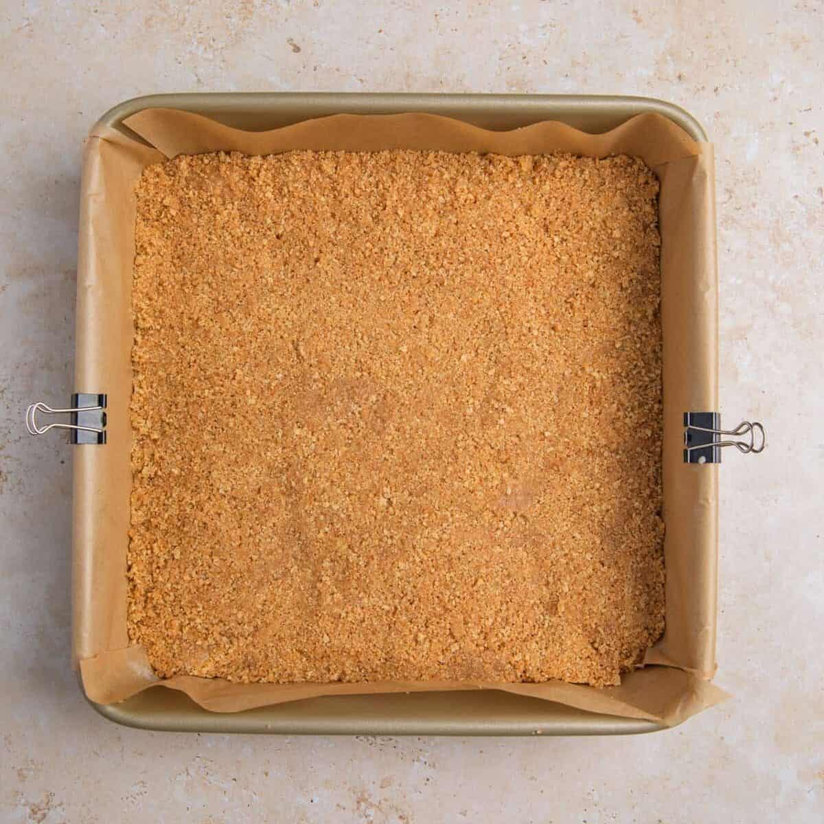 Graham cracker crust pressed into parchment lined pan.