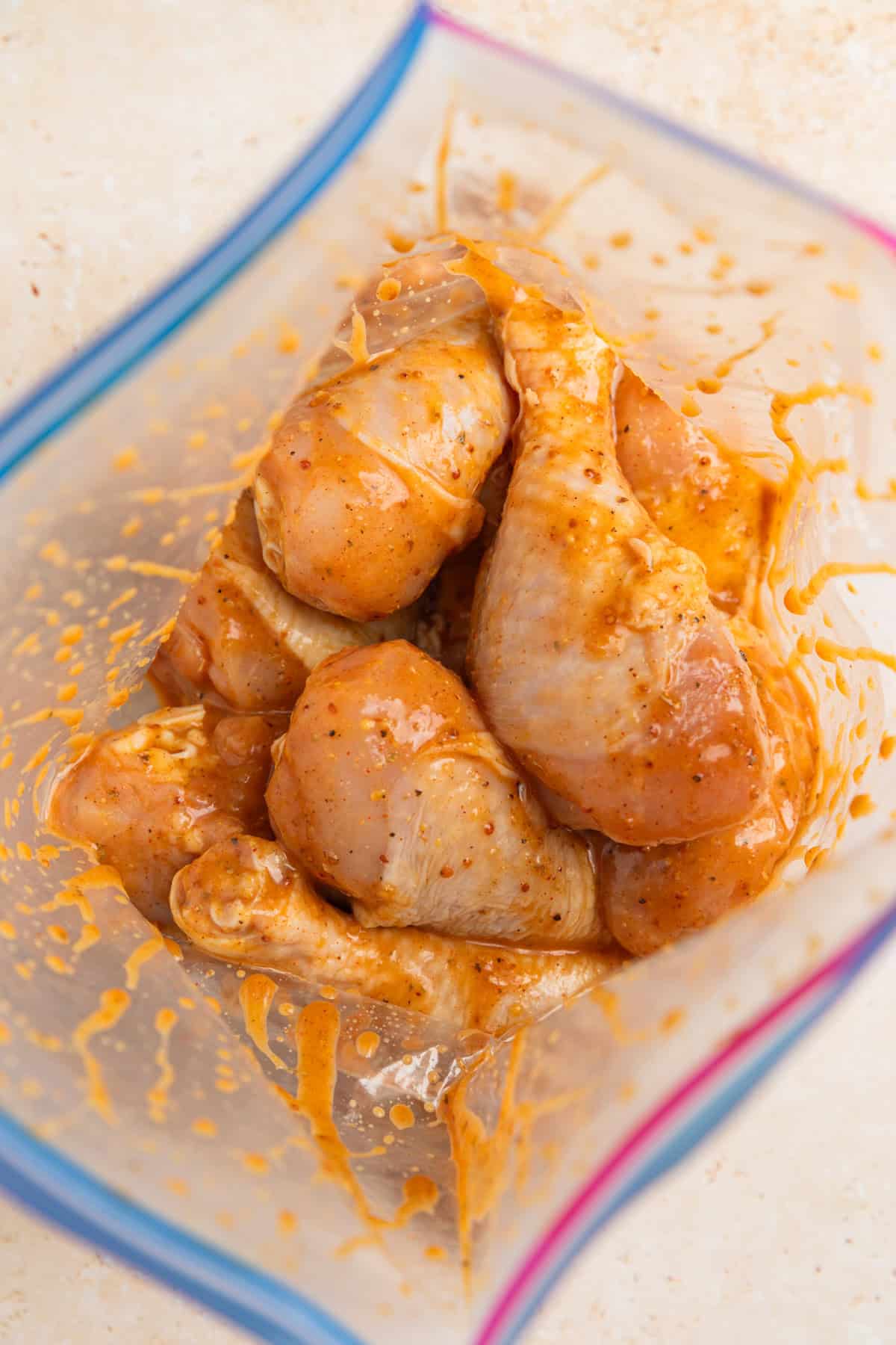 Chicken drumsticks in marinade in plastic bag before sitting.