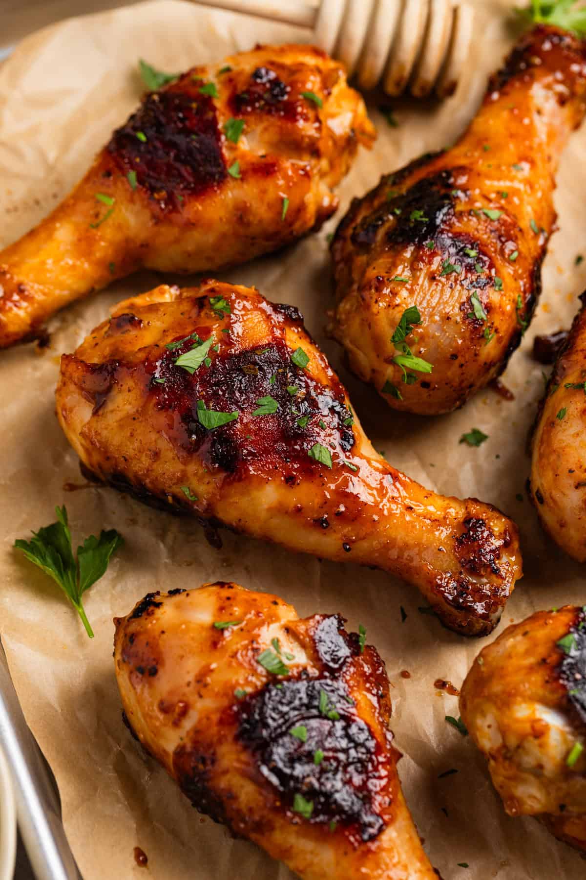 Honey mustard grilled chicken drumsticks on parchment with chopped parsley.