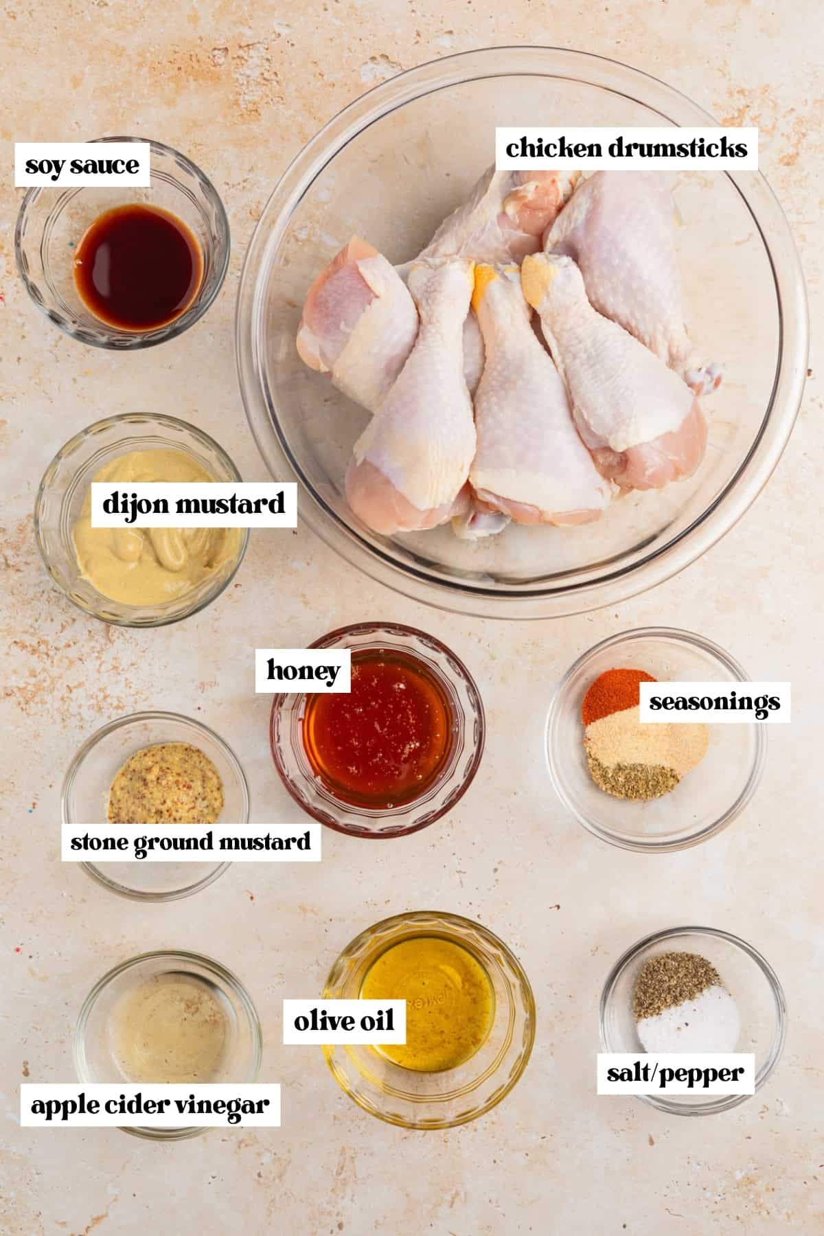 Chicken legs in bowl, honey, spices and other ingredients in bowls prepped for recipe.