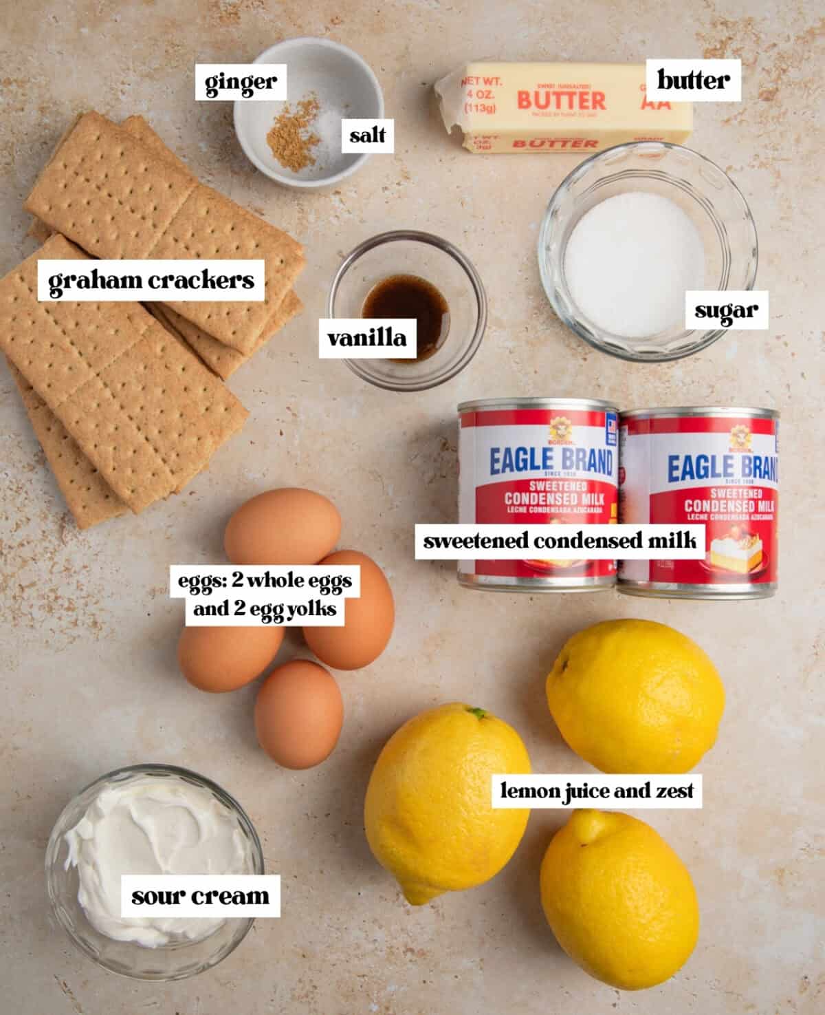 Lemons, graham crackers, eggs and other ingredients labeled on surface.