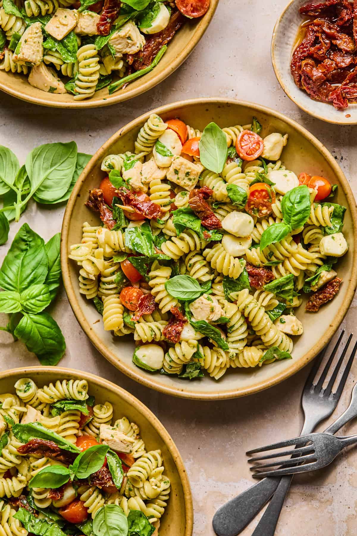 Bowls with pesto pasta salad with chicken and forks.