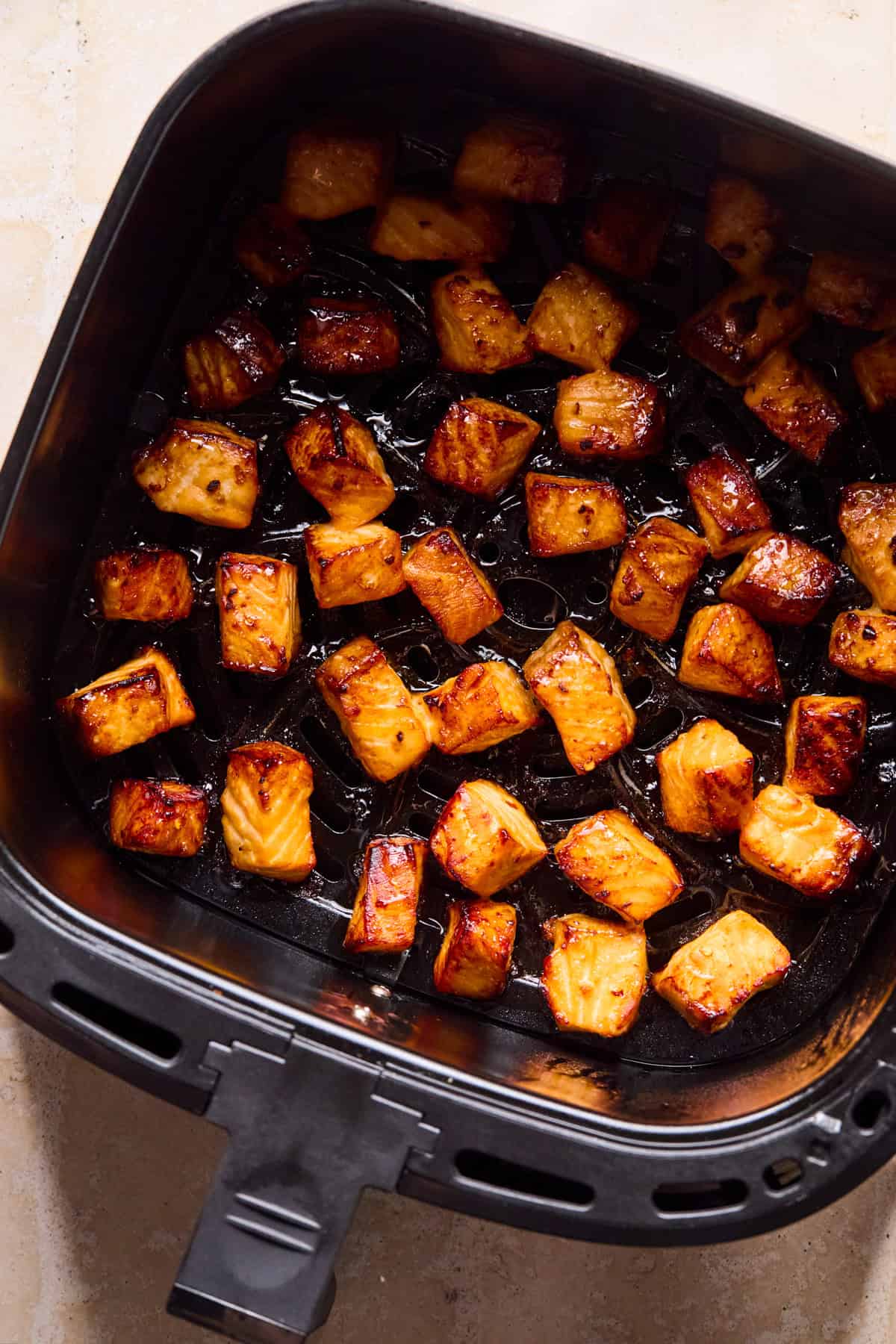 Air fryer with teriyaki salmon bites cooked.