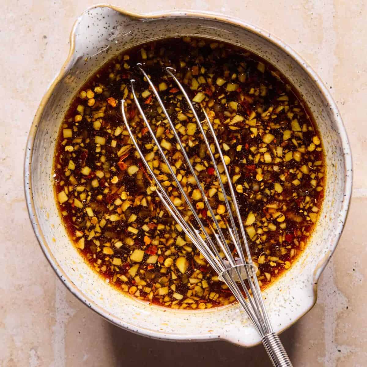 Teriyaki sauce and marinade ingredients in bowl with whisk.
