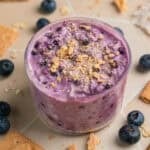 Jar with blueberry cream cheese overnight oatmeal topped with graham crackers.