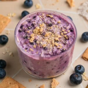 Jar with blueberry cream cheese overnight oatmeal topped with graham crackers.