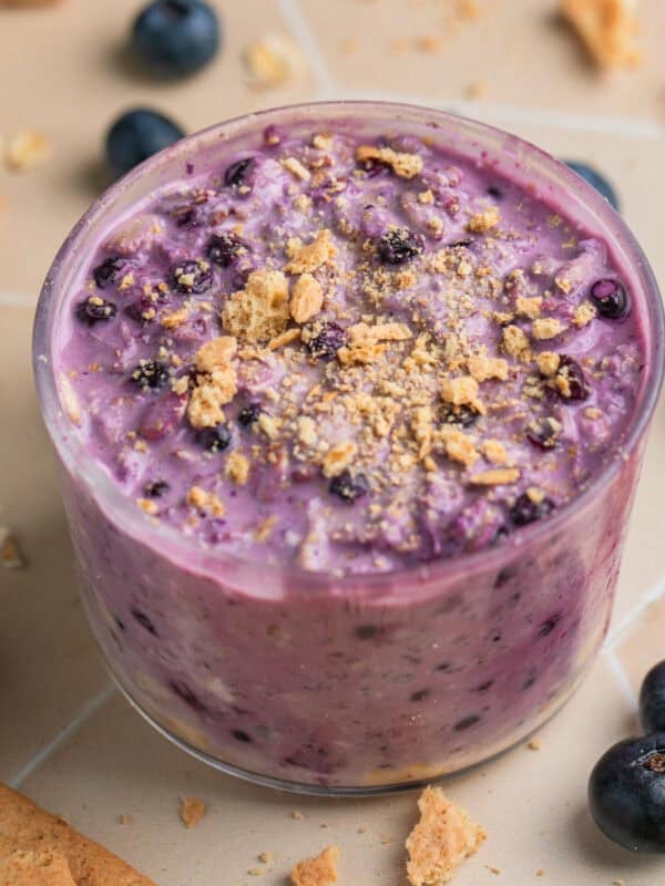 Jar with blueberry cream cheese overnight oatmeal topped with graham crackers.