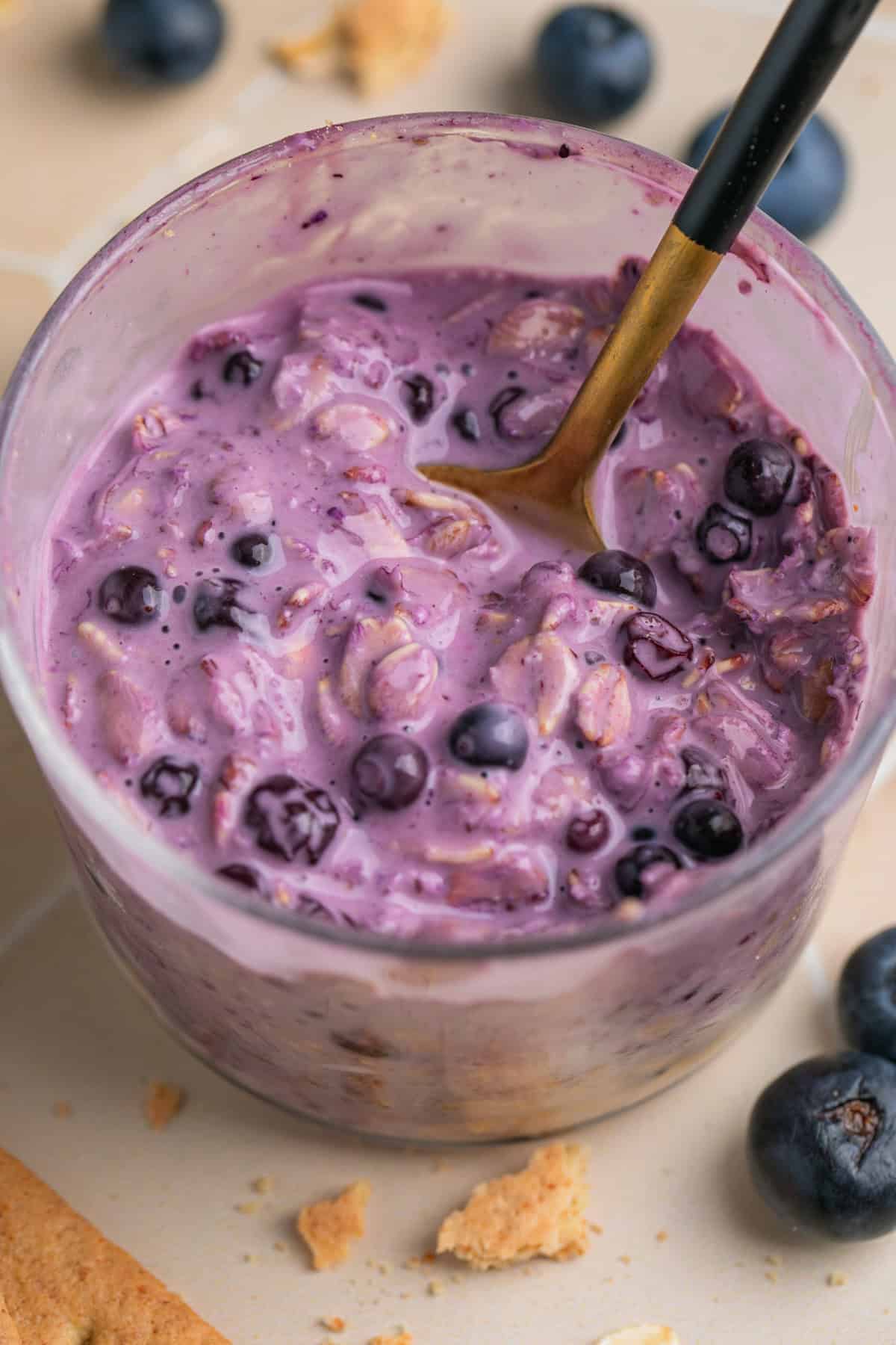 Spoon scooping into cheesecake overnight oatmeal with blueberries.