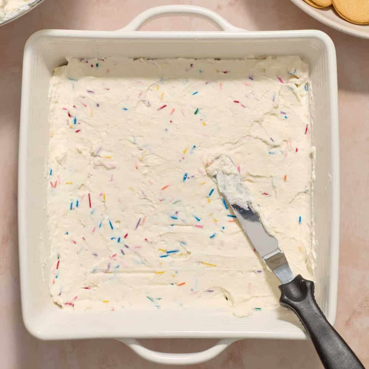 Spread funfetti cream cheese mixture over vanilla cookies with offset spatula.