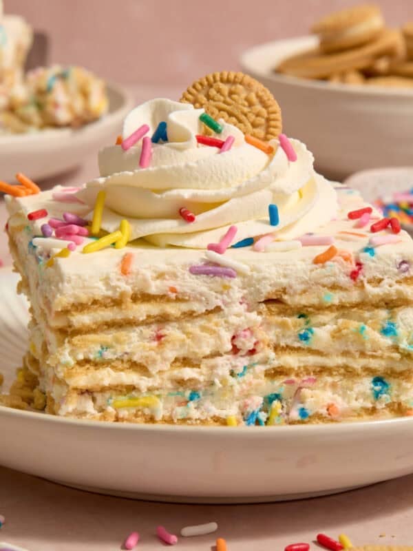 Slice of funfetti icebox cake topped with whipped cream and sprinkles.