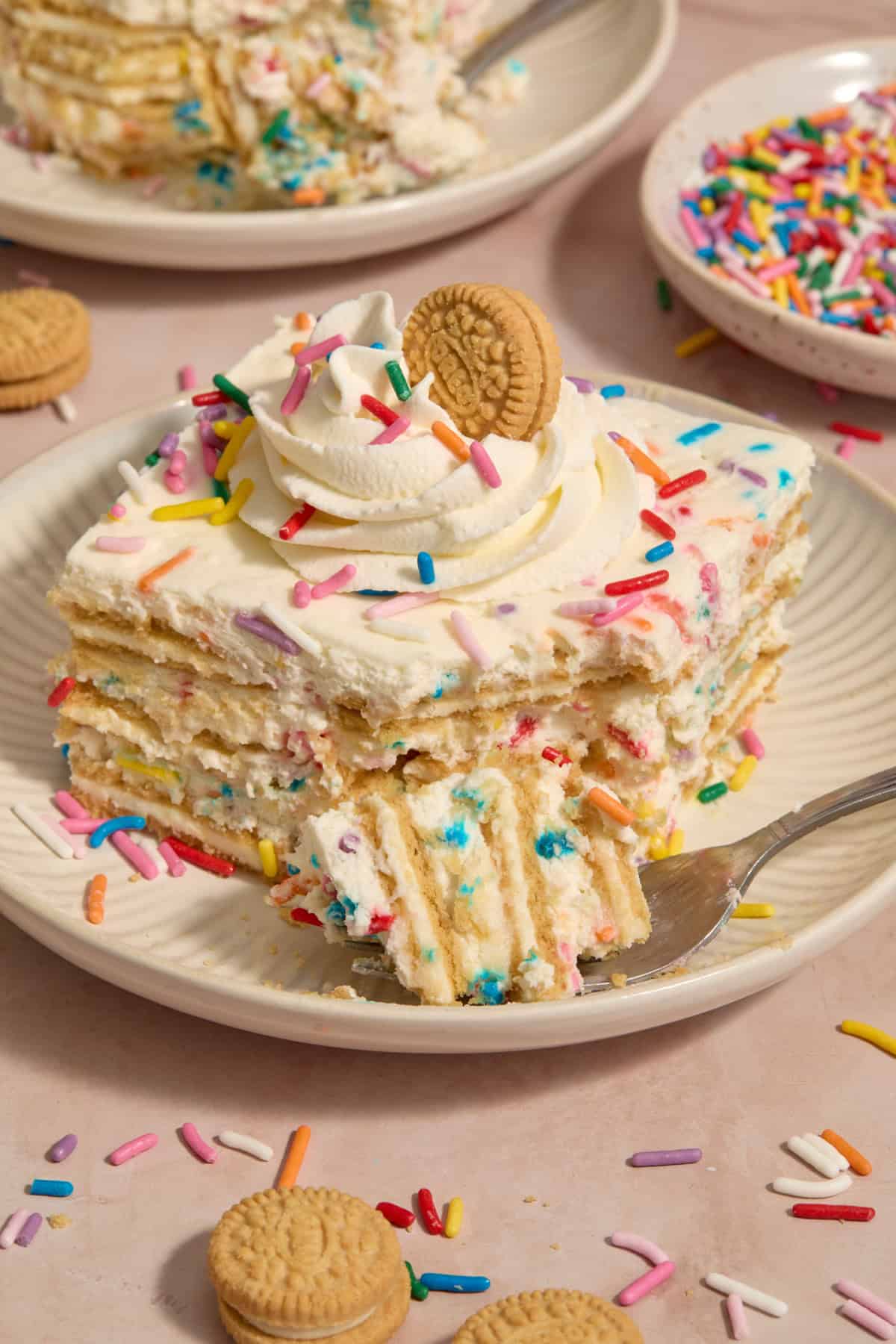 Slice of funfetti layered cake with forkful propped beside the plate.