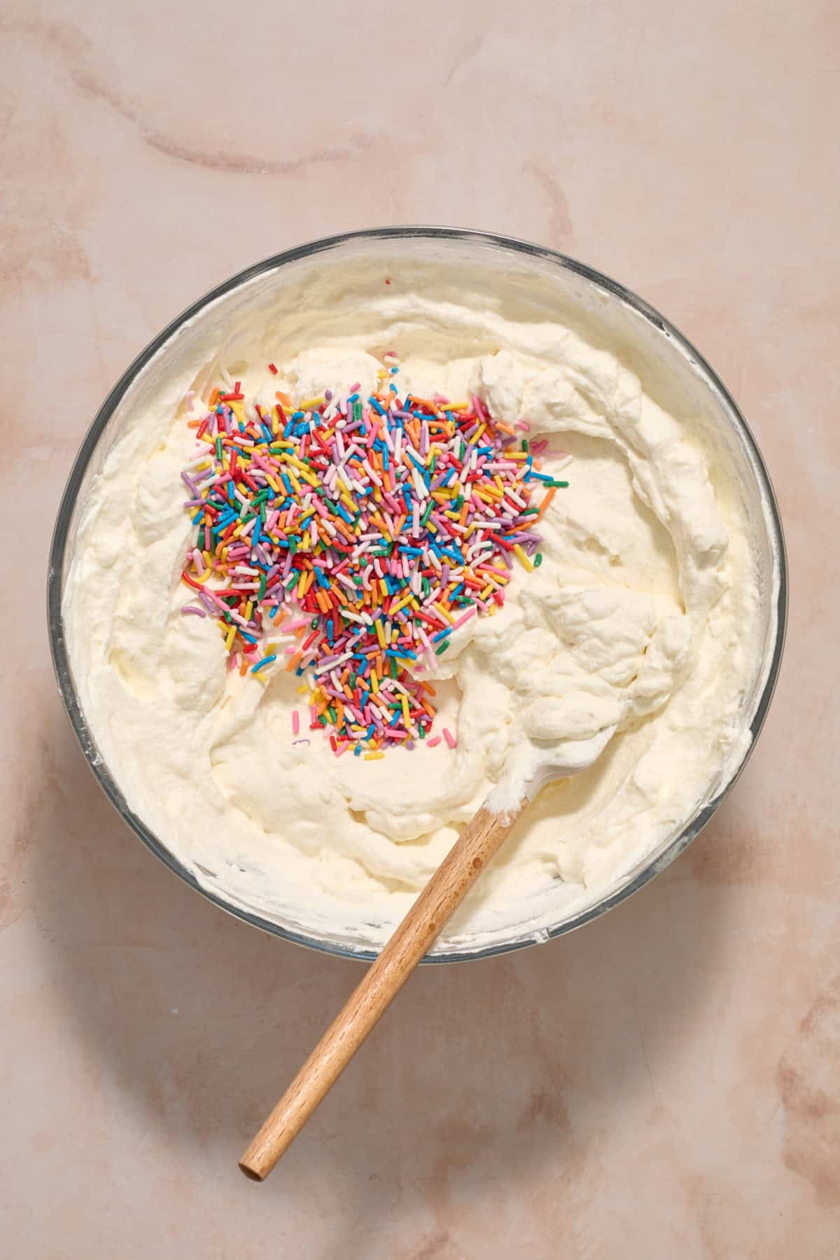 Sprinkles added to cream cheese and whipped cream mixture in bowl.