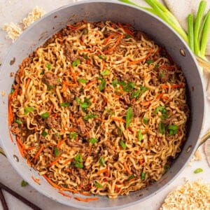 Pan with ground beef ramen topped with green onions.