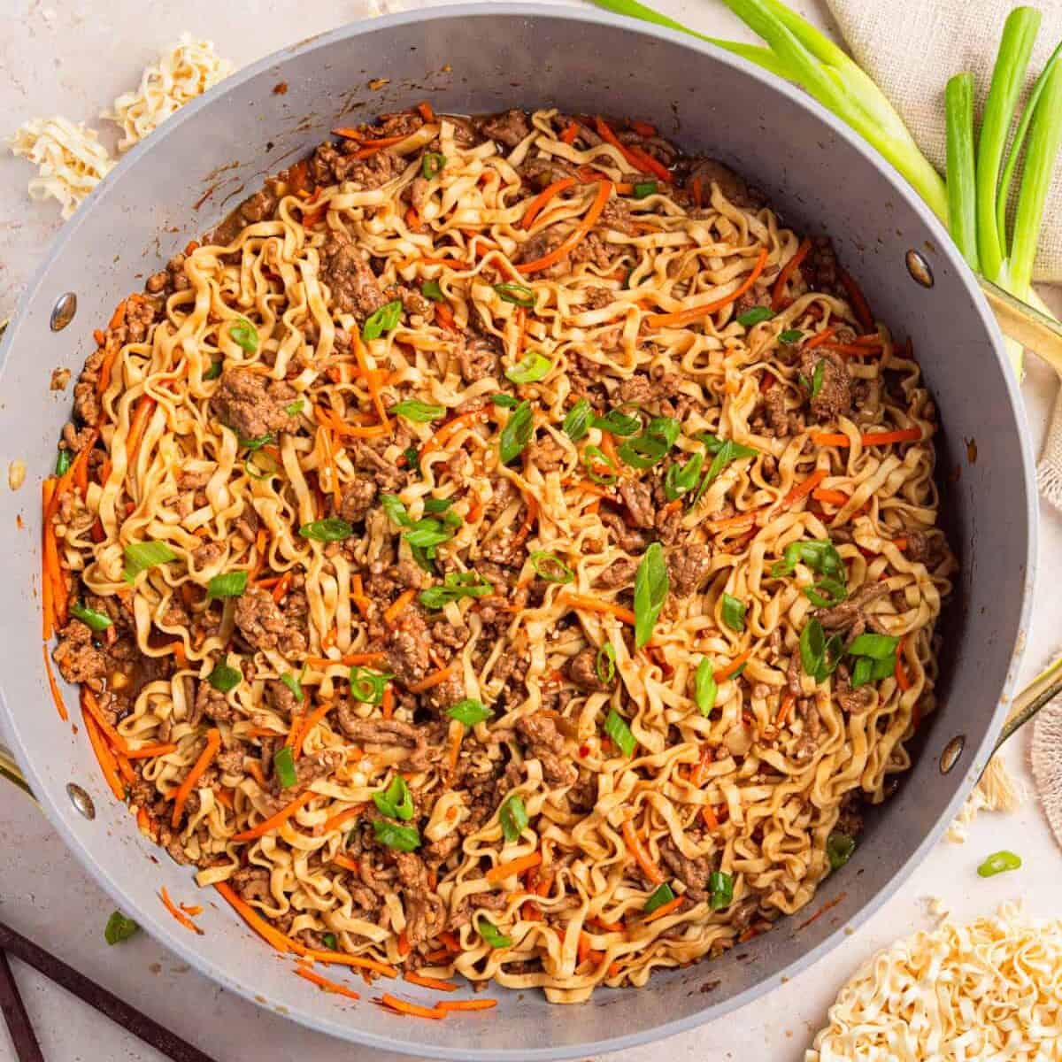 Pan with ground beef one-pot ramen topped with green onions.