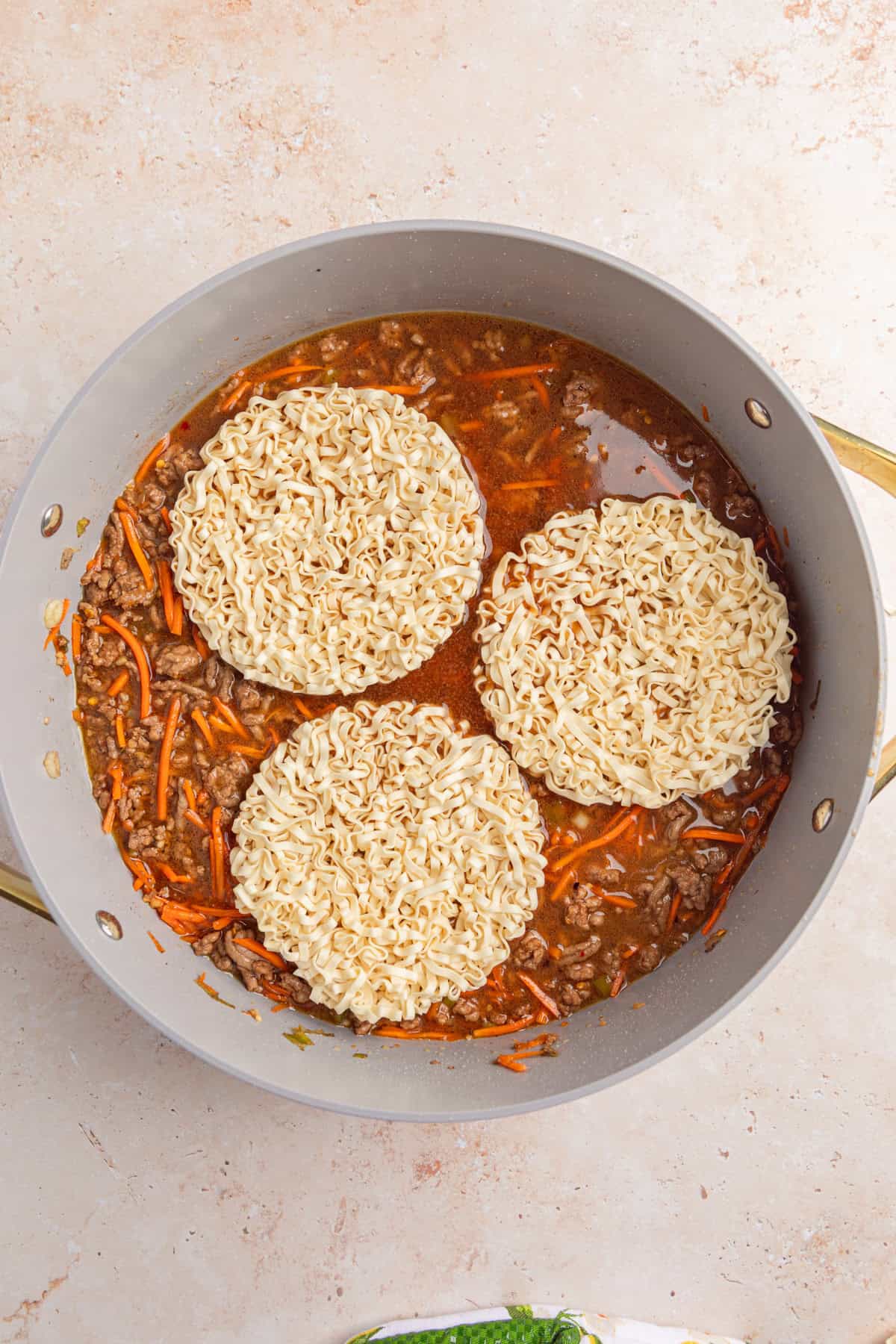 Ramen noodles added to skillet with beef and carrots.