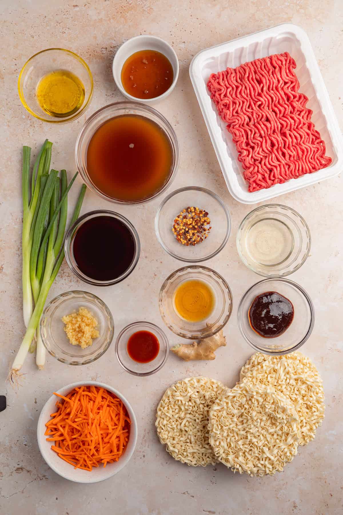 Ground beef, carrots, onions, hoisin sauce and other ingredients arranged on surface for recipe.