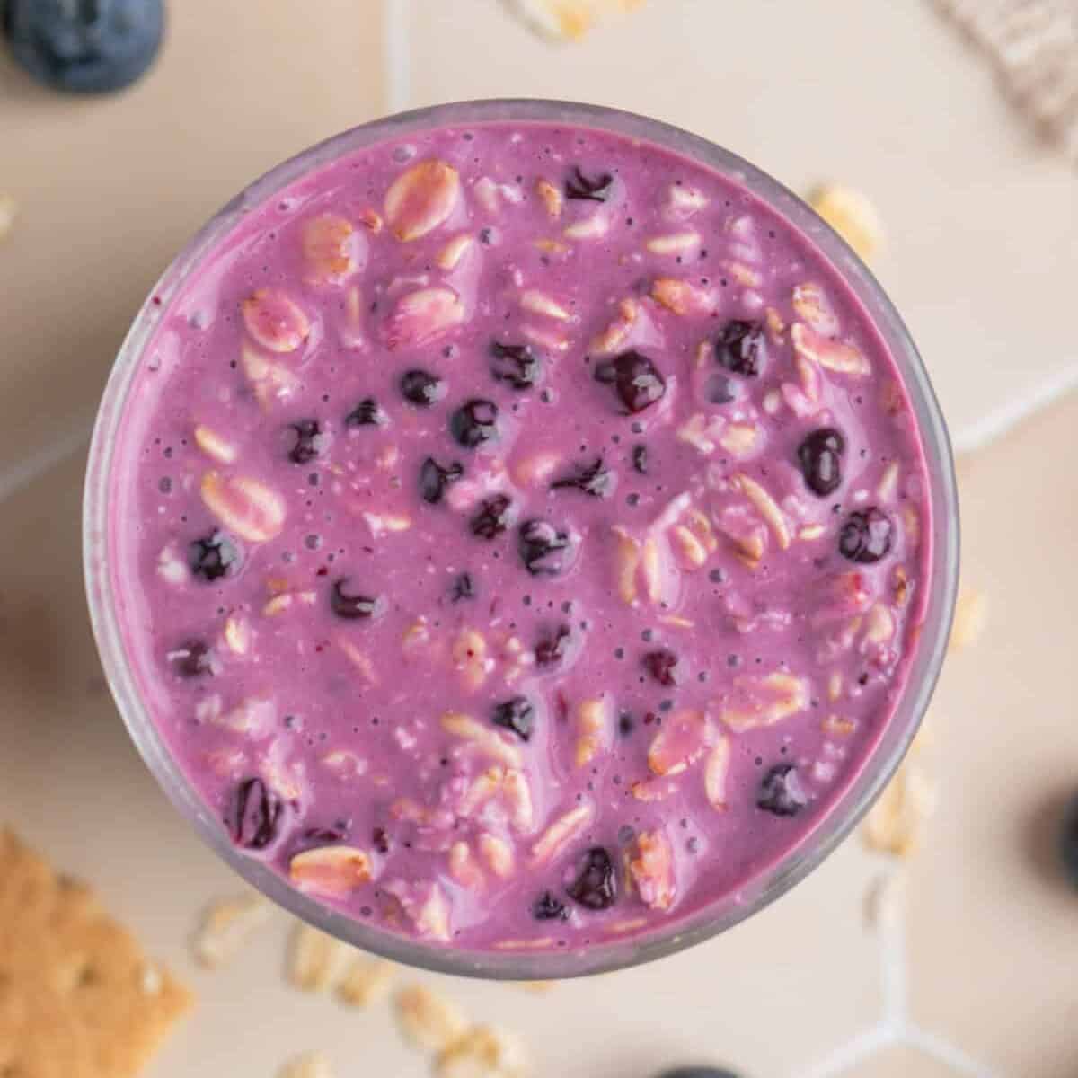 Prepared overnight oatmeal with blueberries and cream cheese in glass cup.
