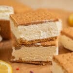 Lemonade ice cream sandwiches stacked on top of each other on parchment.