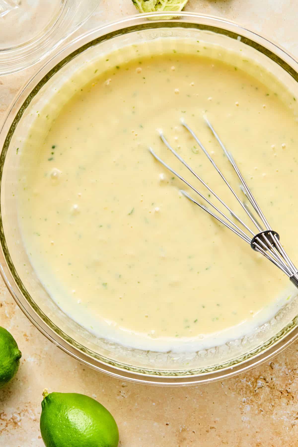 Lime zest, lime juice, eggs, sweetened condensed milk and other ingredients whisked in bowl.
