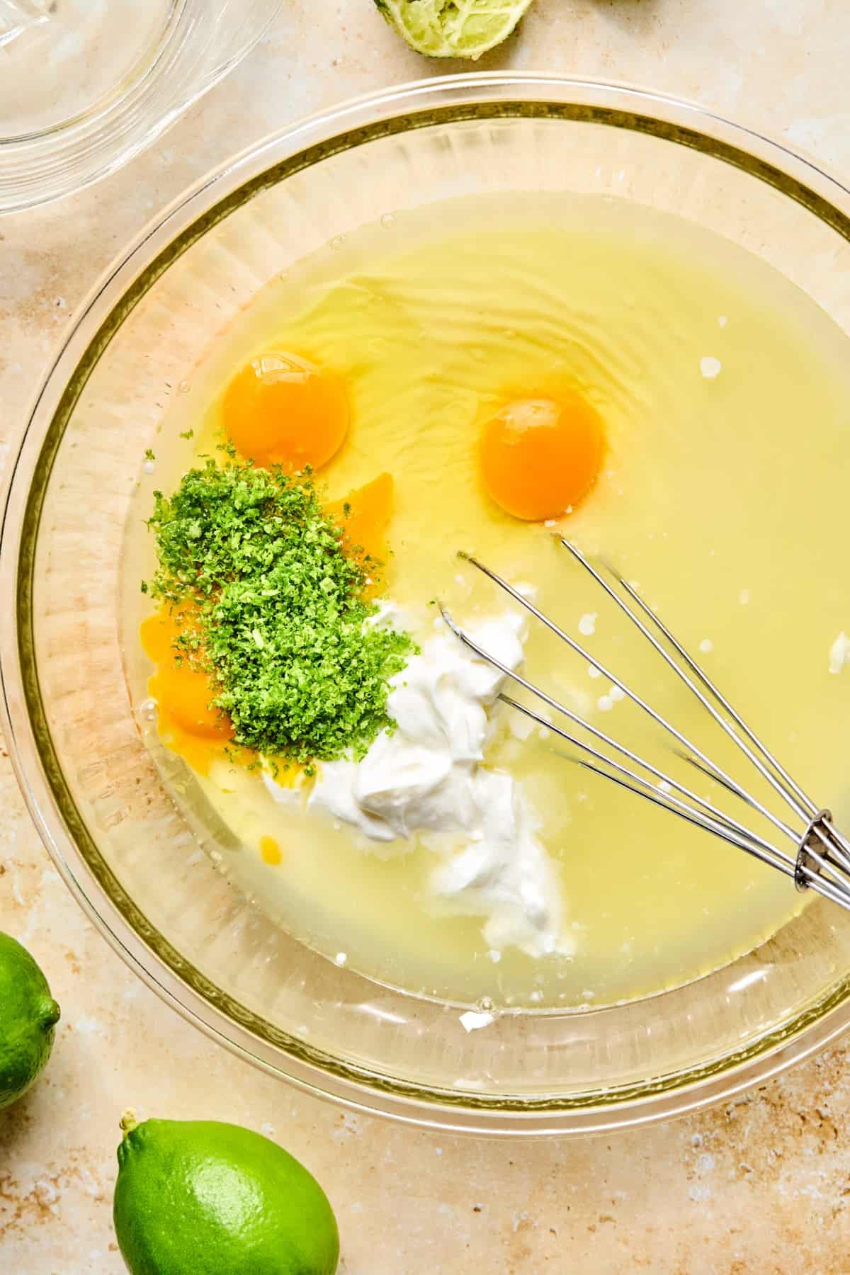 Lime zest and juice, eggs, sour cream and other ingredients in bowl.