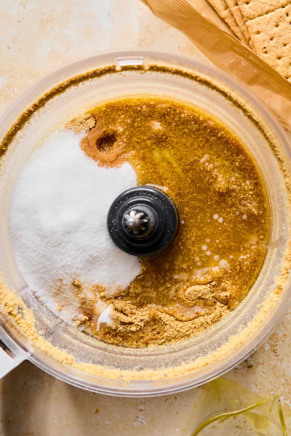 Butter, sugar and ginger added to graham cracker crumbs in food processor.