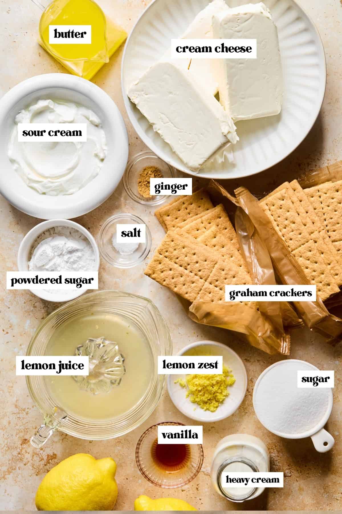 Graham crackers, cream cheese, sugar, lemon zest, and other labeled ingredients on surface.