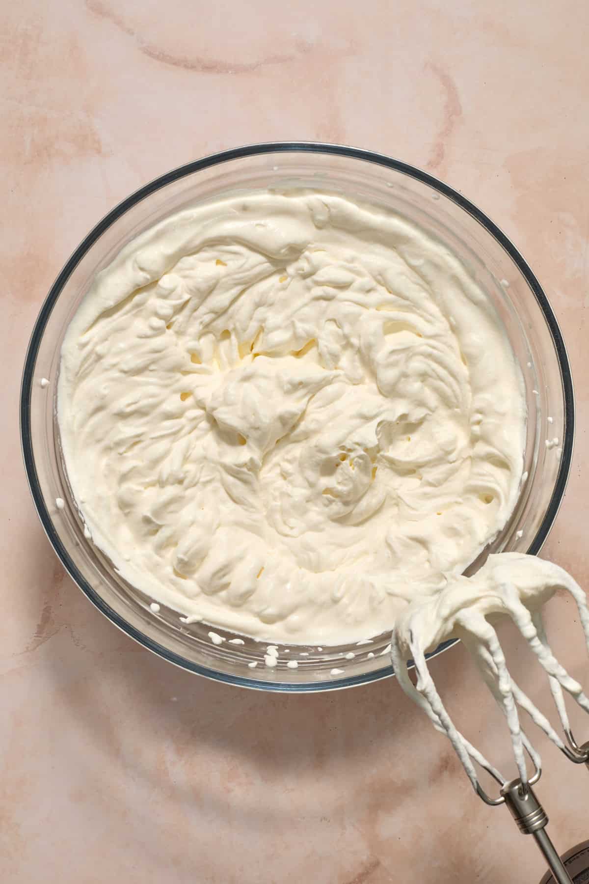Whipping cream whipped to stiff peaks in mixing bowl.