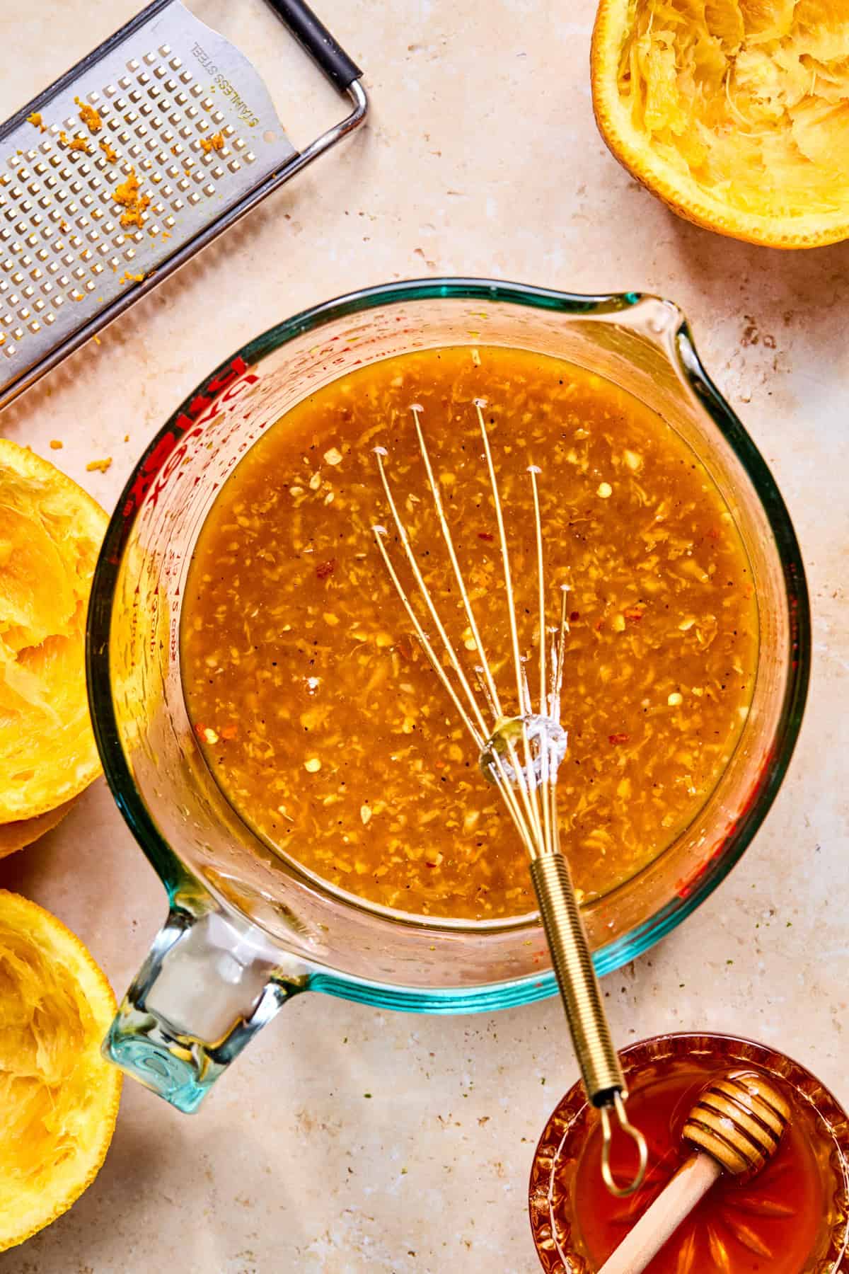 Whisked orange chicken sauce mixture in glass measuring cup.