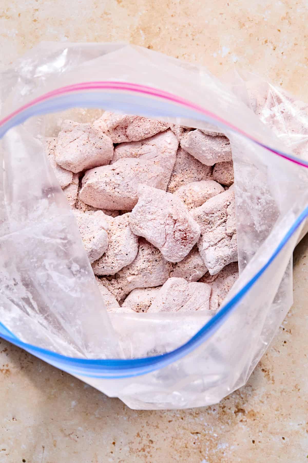 Plastic bag with seasoned and coated chicken.