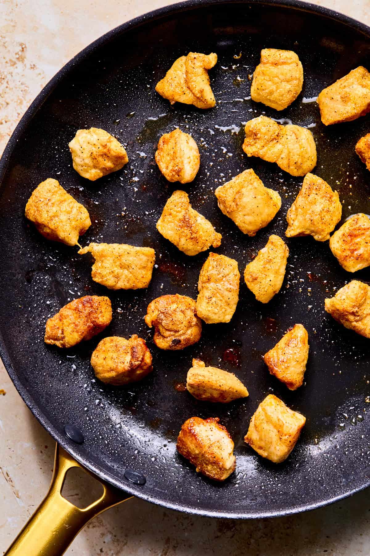 Browned chicken bites in skillet.