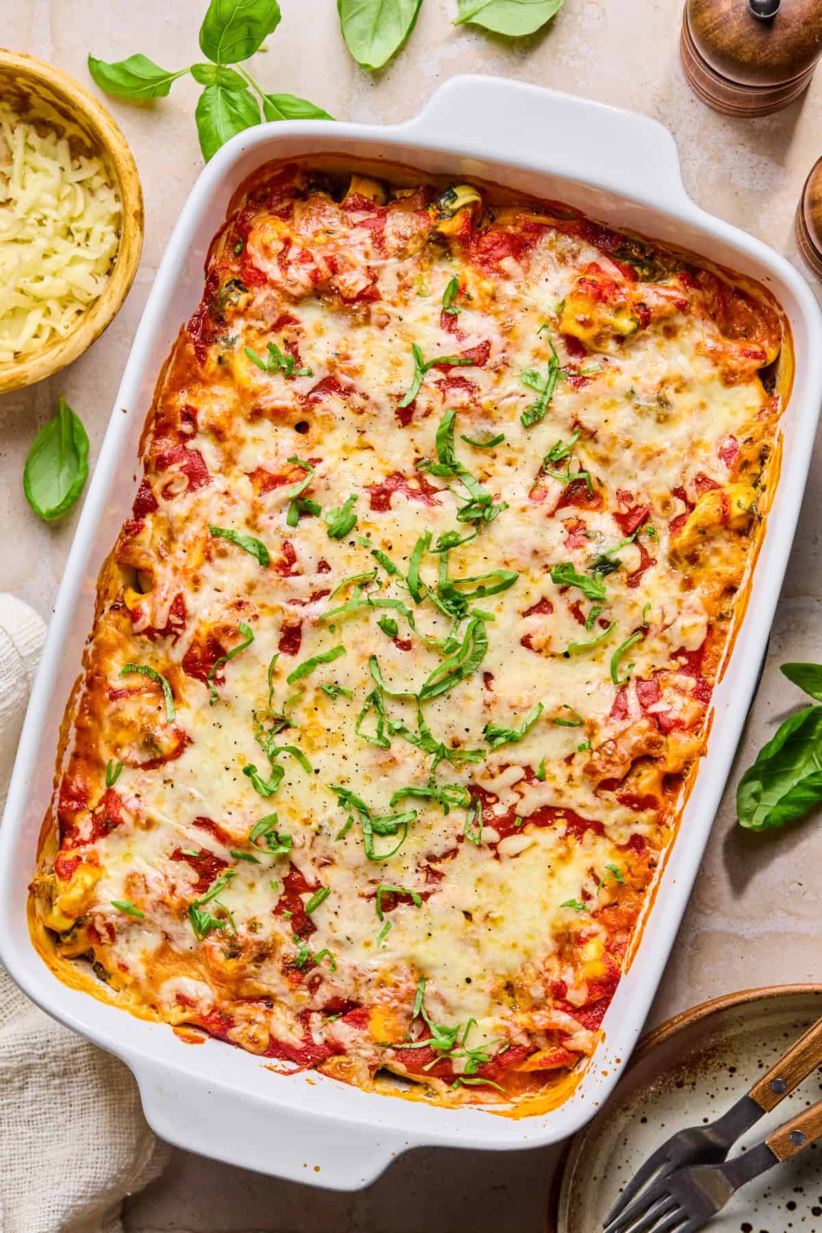 Spinach and ricotta cheesy tortellini baked pasta with chopped basil on top.