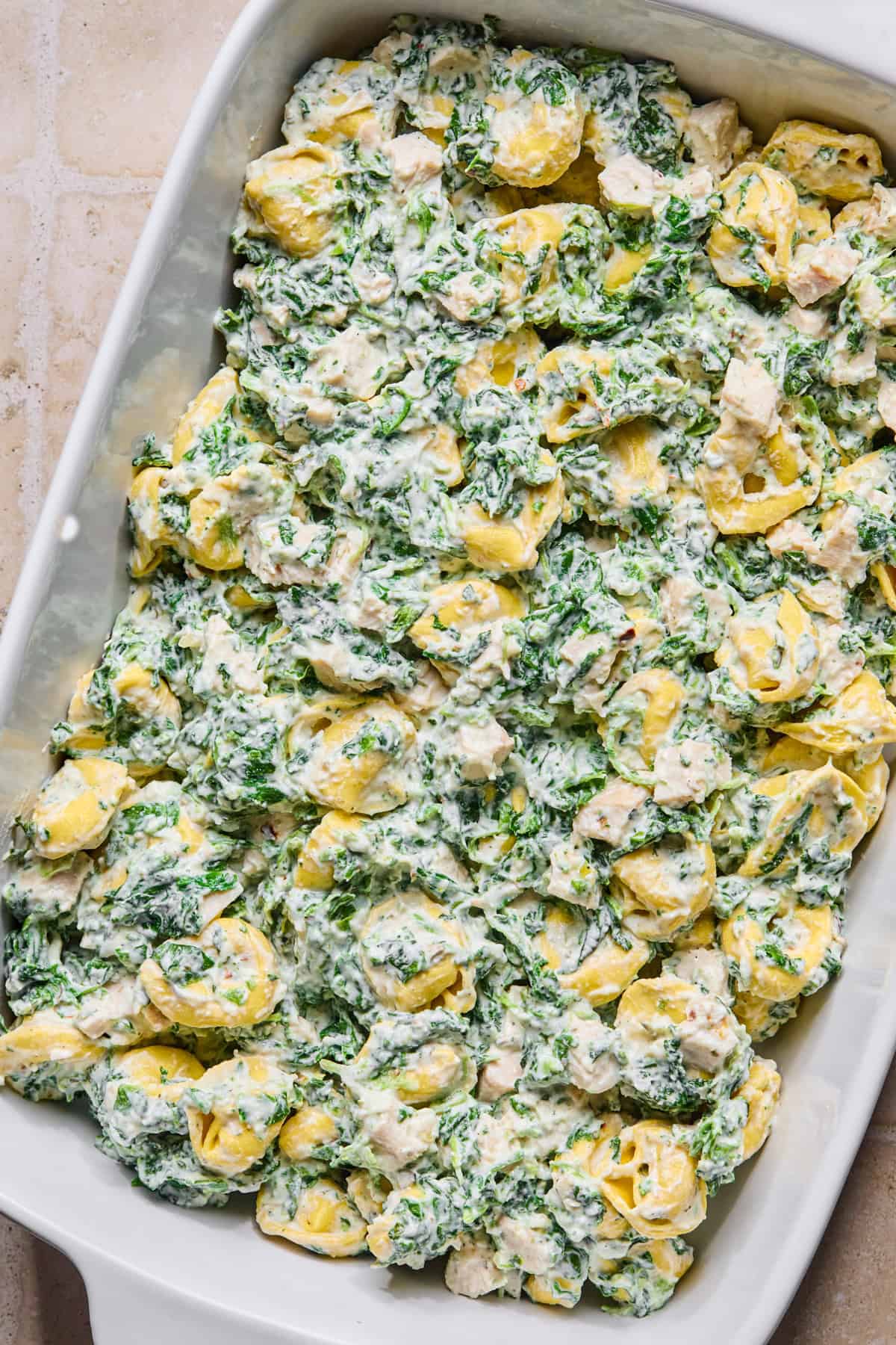 Spinach tortellini mixture in casserole dish.