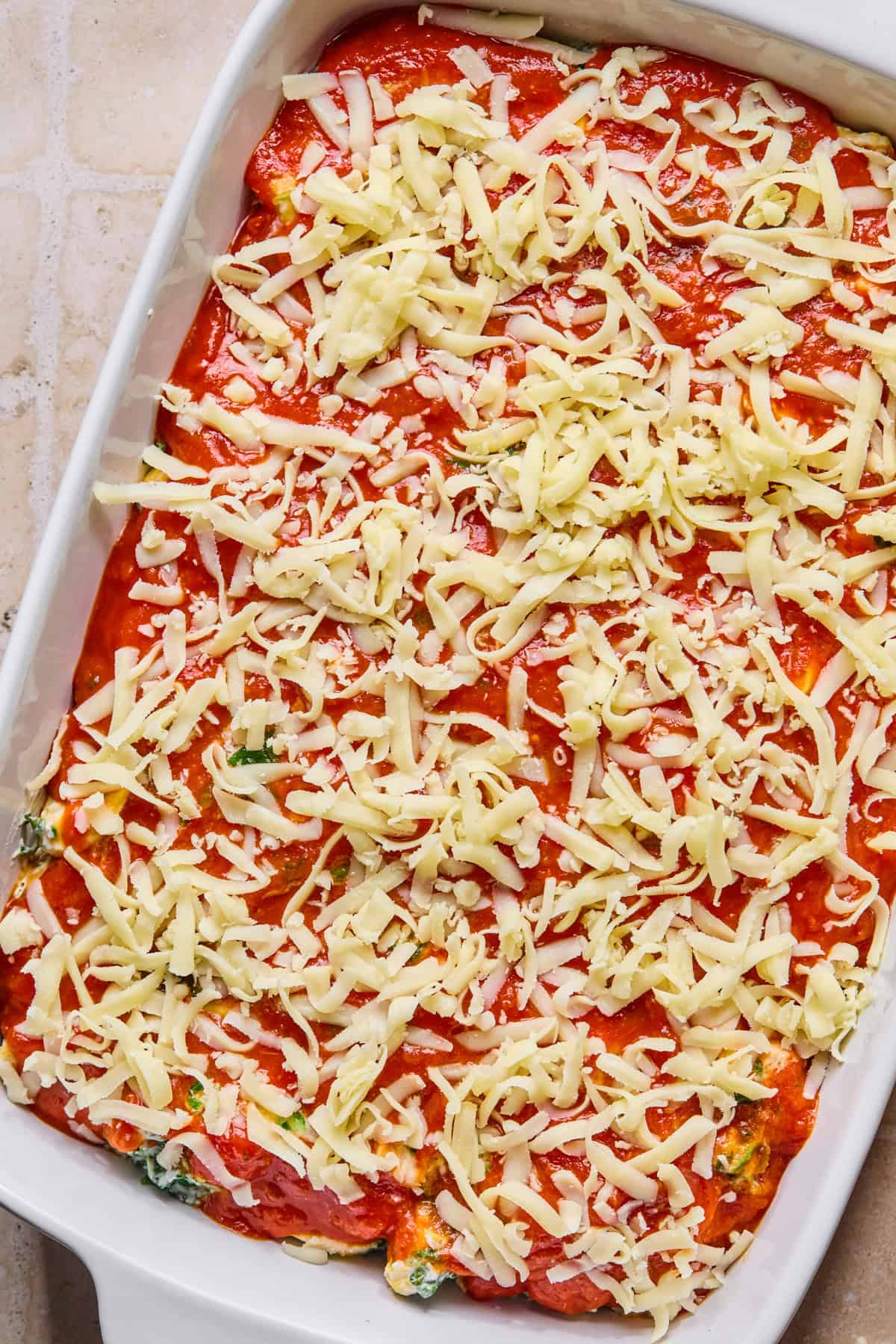 Cheese covering marinara in pan with pasta.