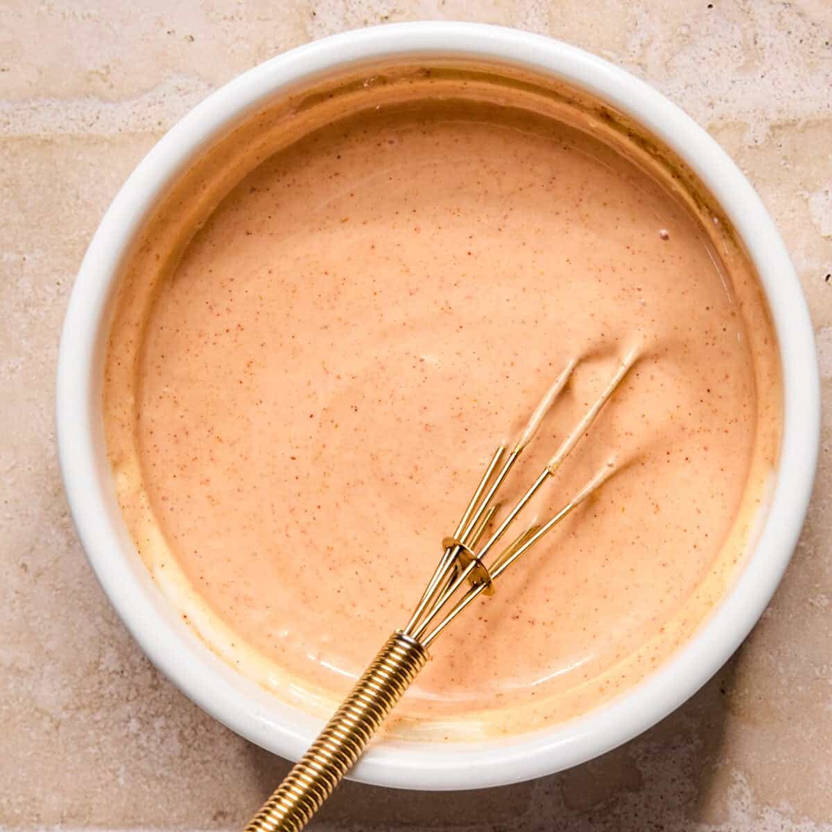 Special burger sauce in white bowl with whisk.