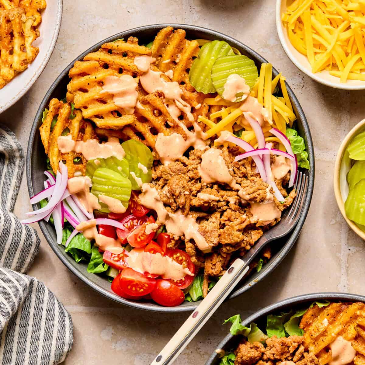 Turkey burger bowls with waffle fries, tomatoes, lettuce and special sauce over top.