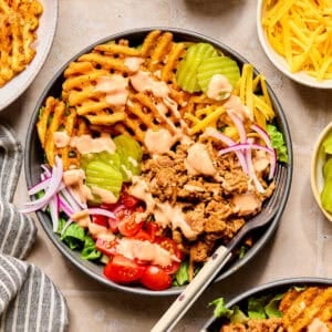 Bowl with ground turkey topped with burger sauce, waffle fries and other burger toppings.