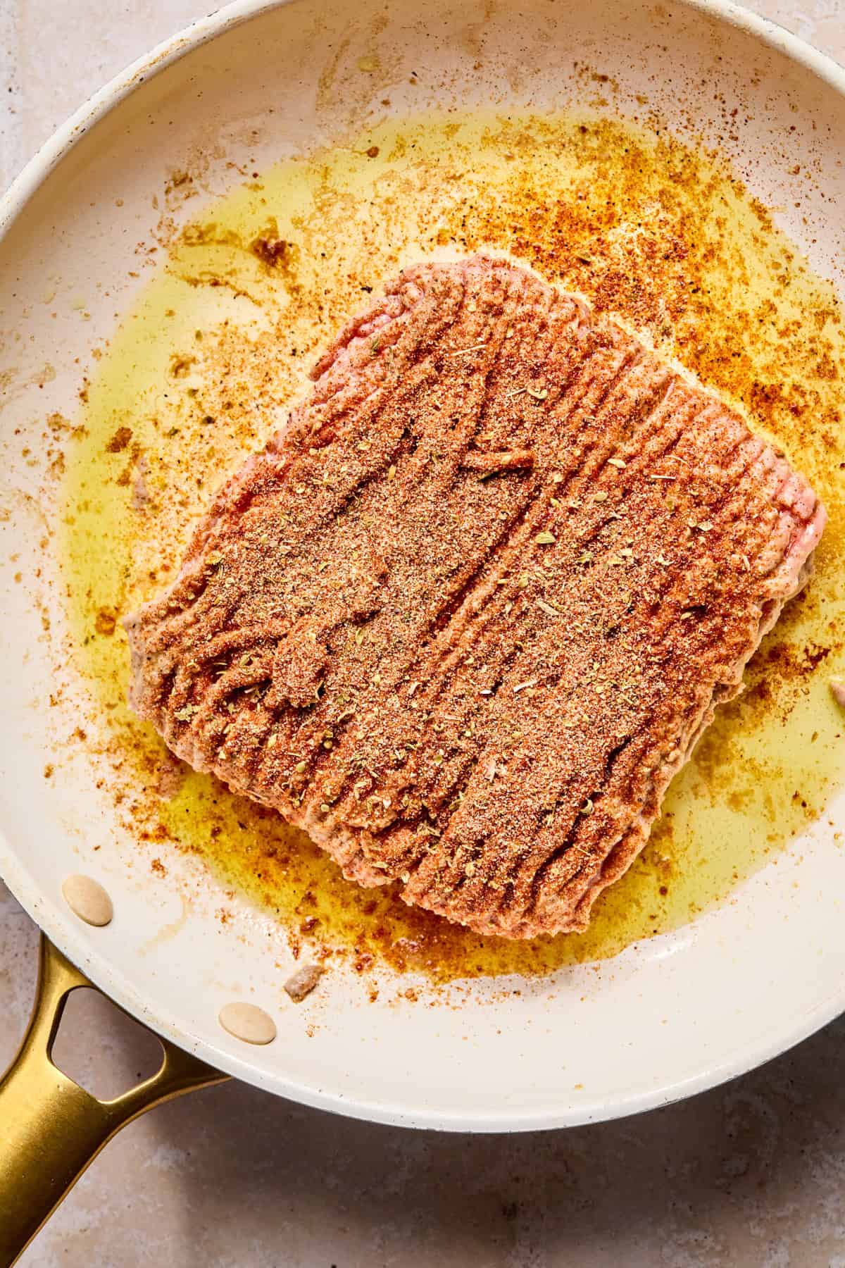 Ground turkey in skillet with seasoning on it.