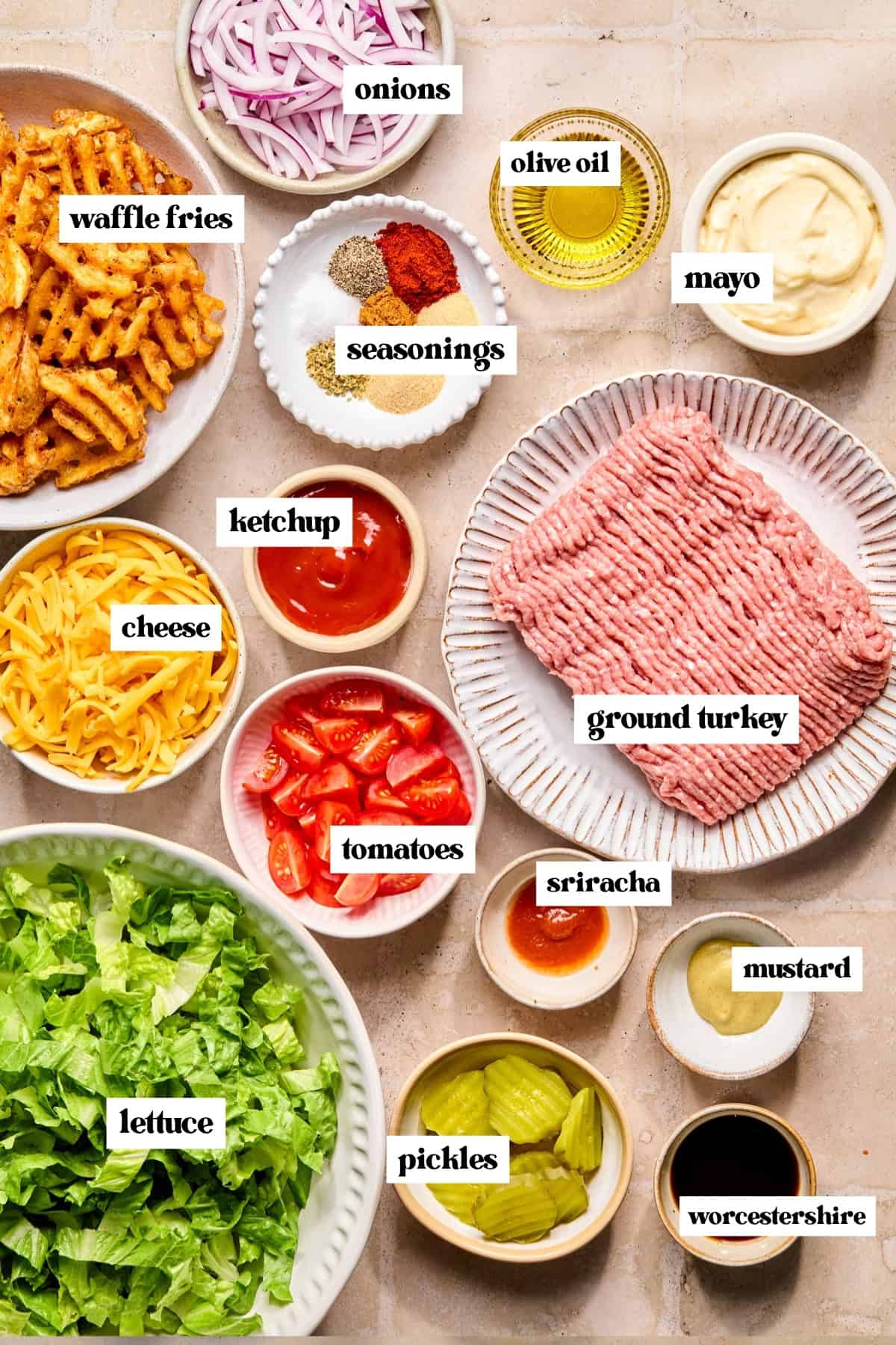 Meat, mayo, veggies, seasonings and other ingredients on surface labeled.
