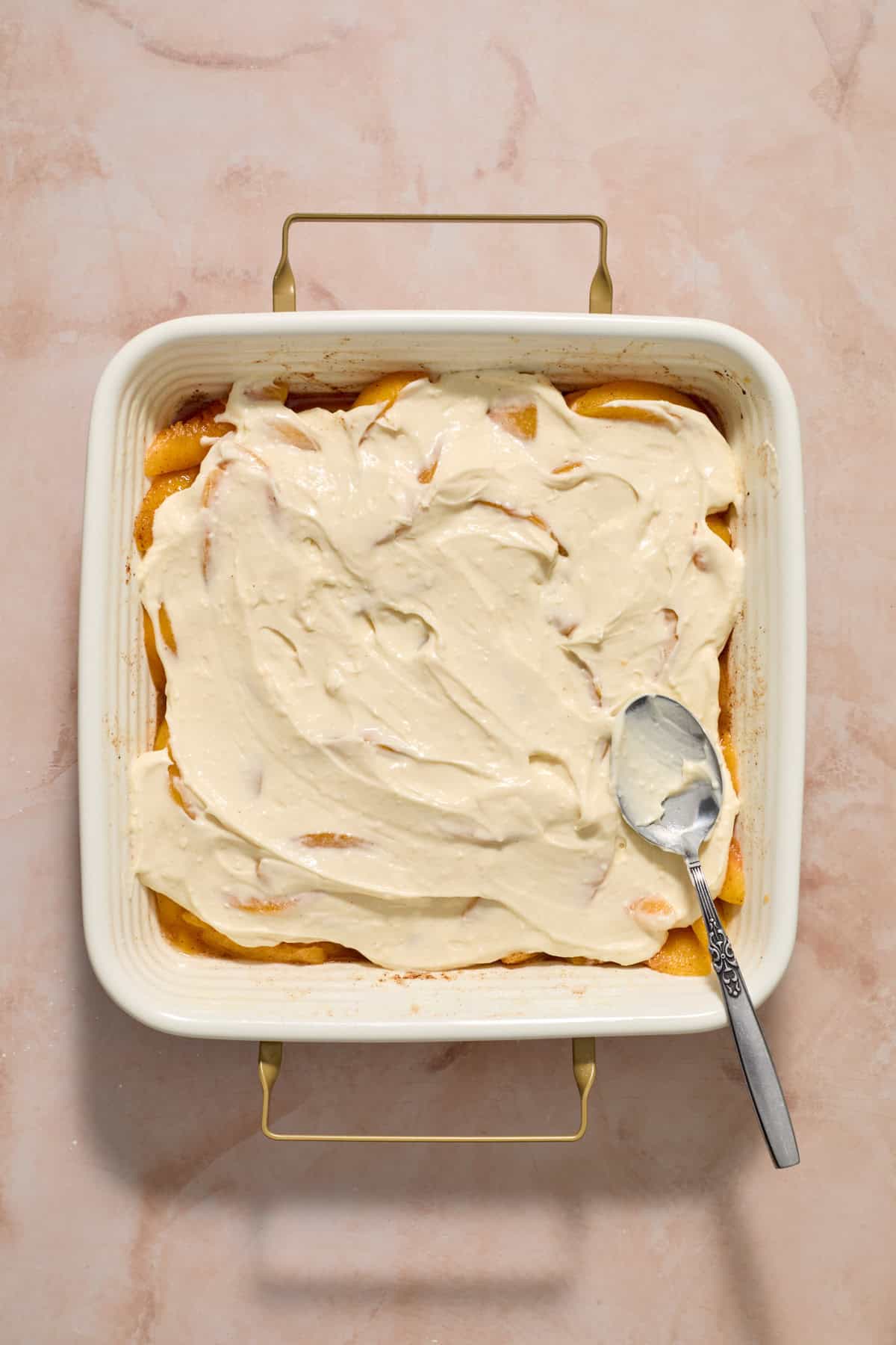Cheesecake mixture spread over peaches.