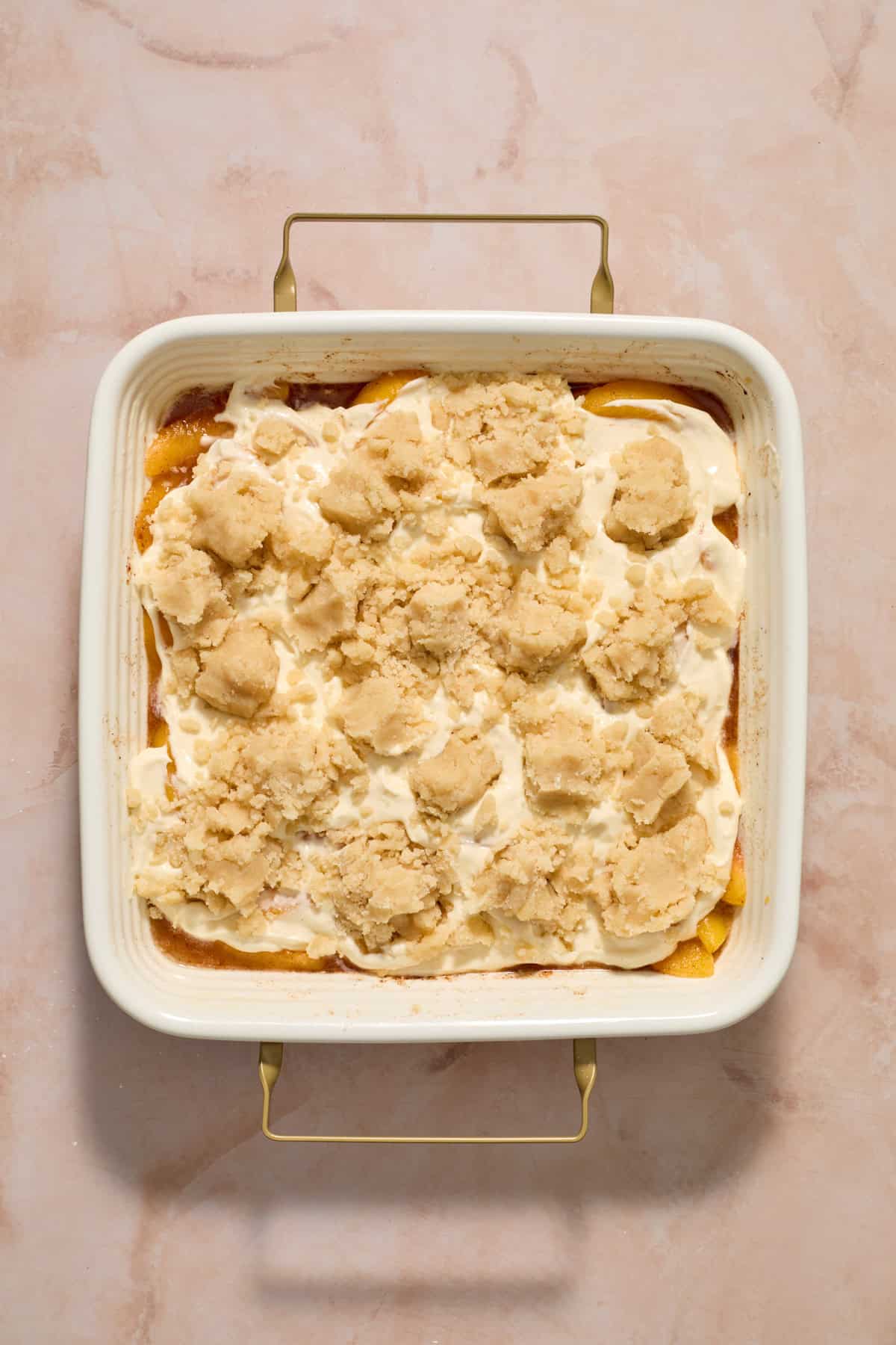 Cobbler crumbles sprinkled over peach and cheesecake layer before baking.