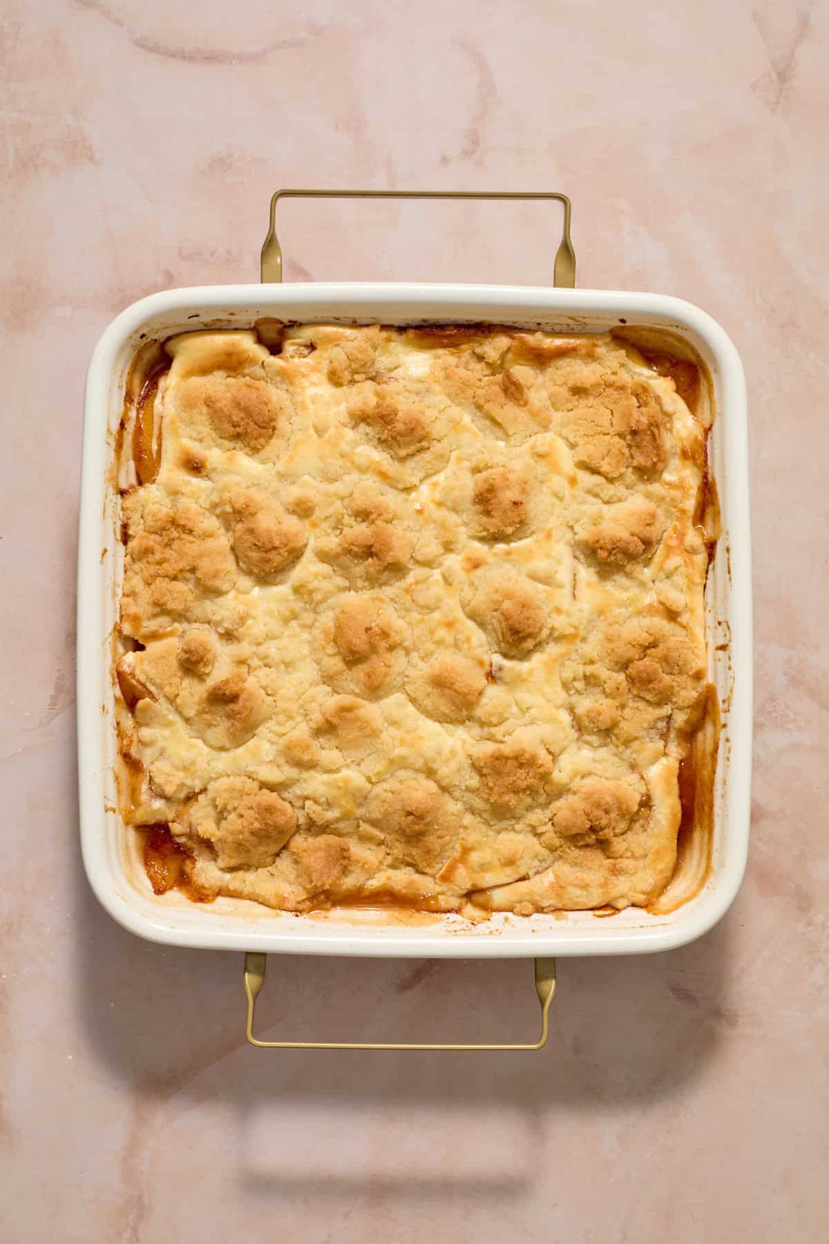 Baked cream cheese peach cobbler in pan.