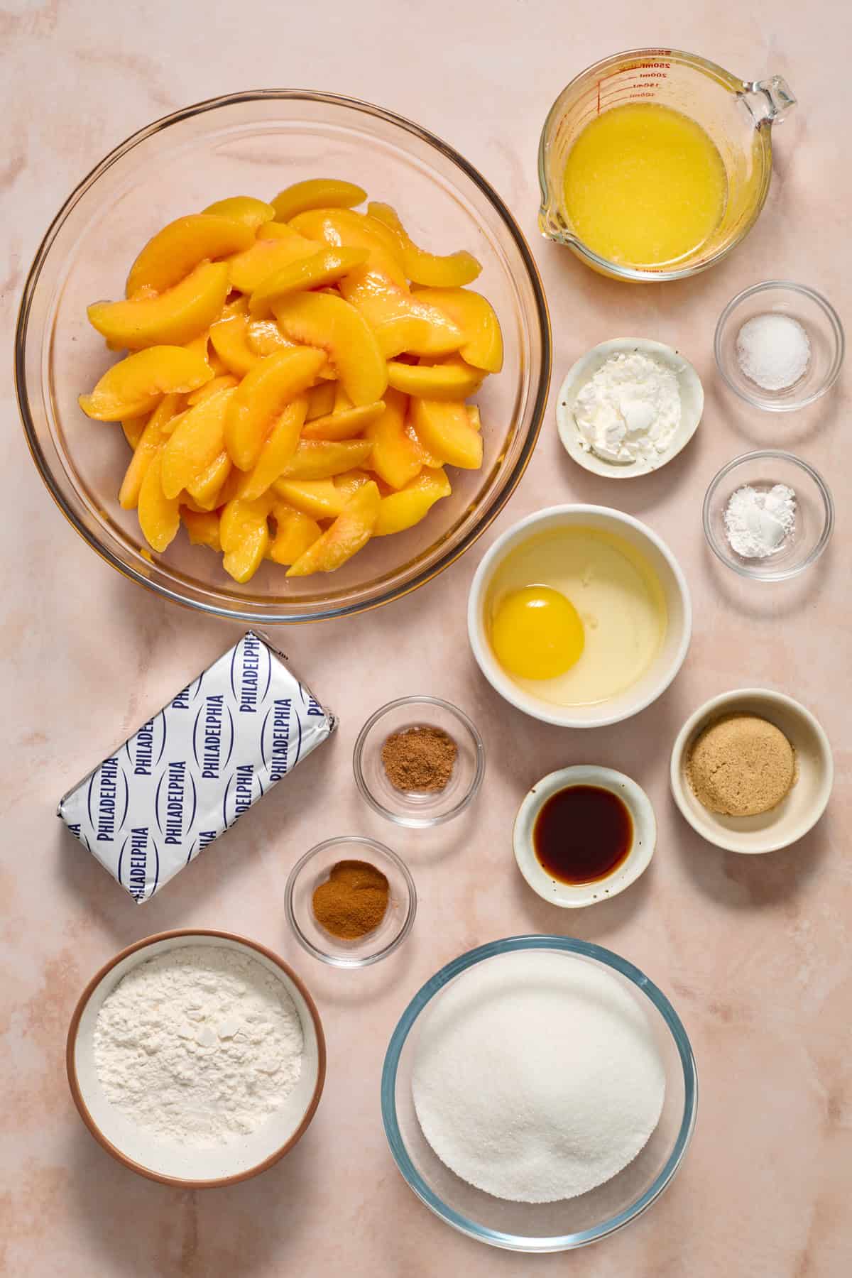 Cream cheese, sliced peaches, sugars, egg and other ingredients on surface.